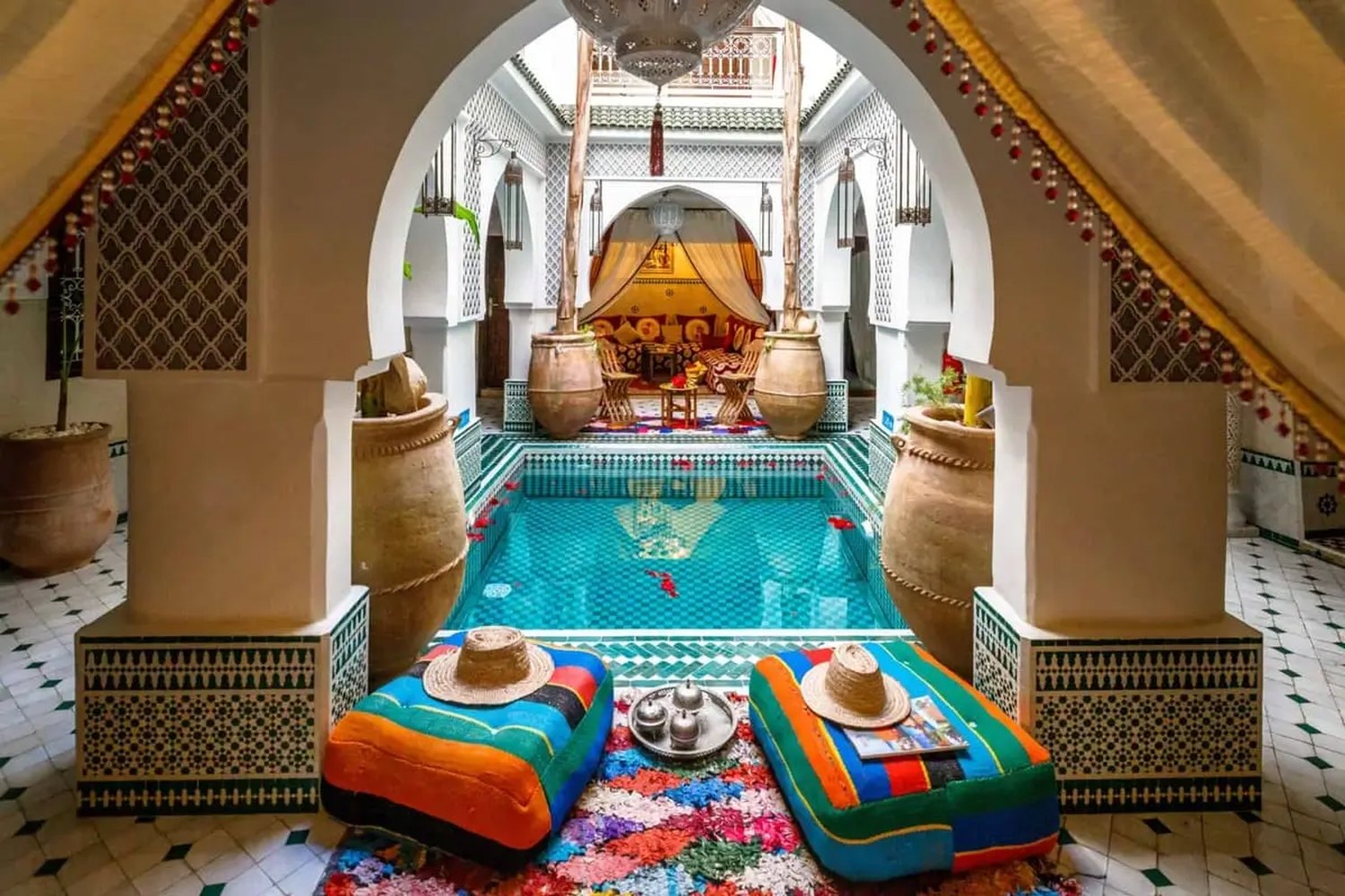 Turquoise pool in the courtyard of a luxury Marrakech riad framed by Moroccan arches and palms